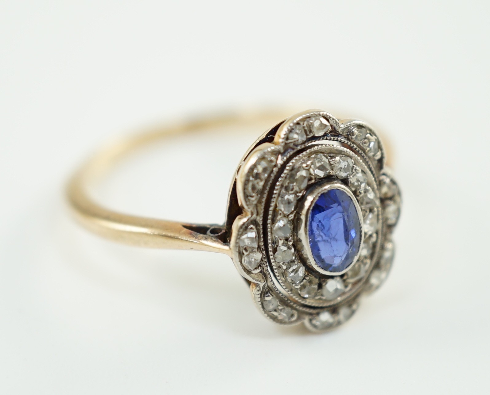 An early 20th century gold, sapphire and millegrain set rose cut diamond set oval cluster ring